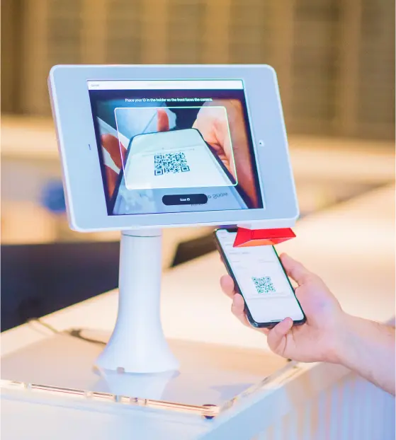 Person scanning QR code with smartphone at a kiosk