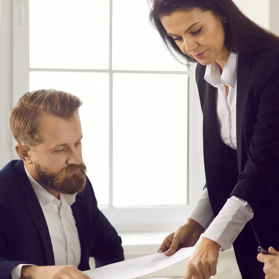 Two business professionals discussing documents in formal attire
